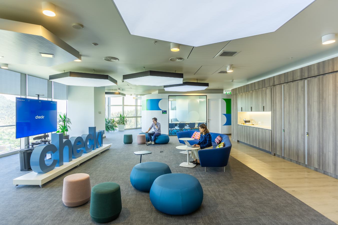 Checkr Offices - Central social hub with branded signage, blue poufs, and flexible seating - Contract Workplaces.jpg